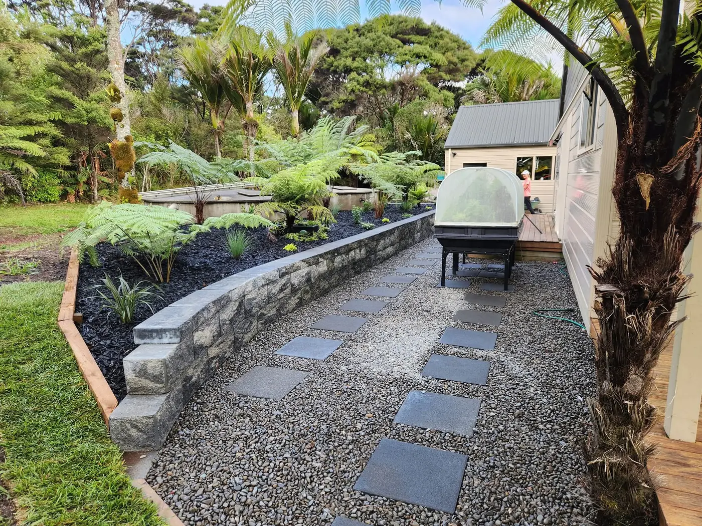A paved path winding through a planted West Auckland garden
